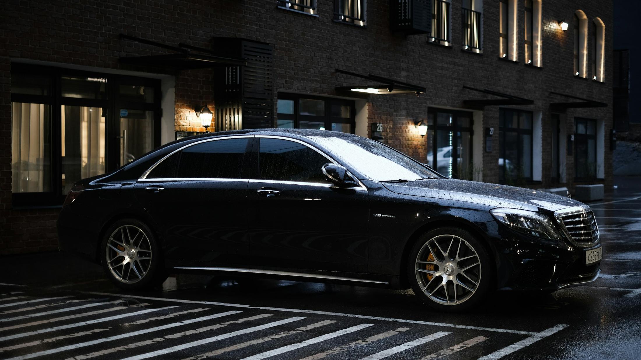 Black Mercedes-Benz sedan waiting at a hotel entrance at night